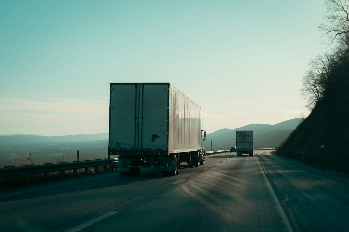 Two semi trucks driving on an interstate highway